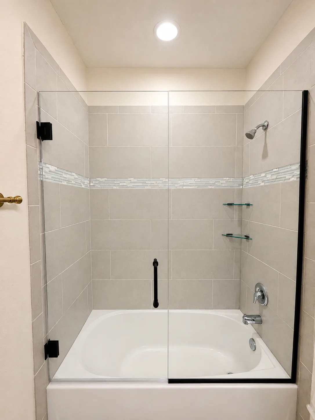 Frameless glass tub panel with black wall-mounted hinges and exposed polished glass edges in a Sarasota bathroom