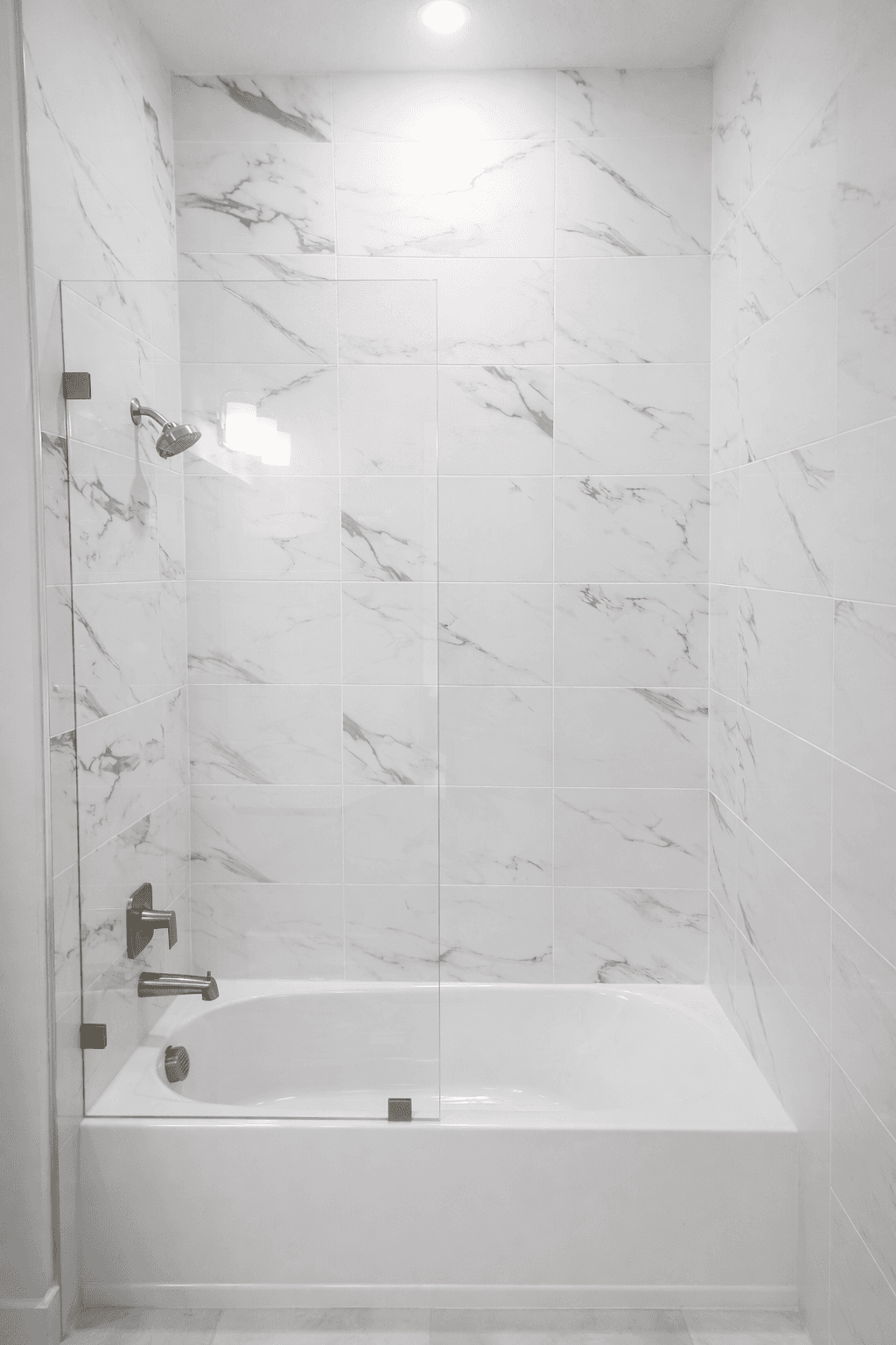 Fixed panel shower with marble tile walls and brushed nickel fixtures over a freestanding tub